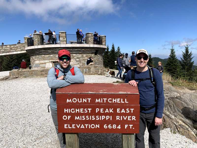 A picture of Trent and Trevor Harmon standing next to the sign at the top of Mount Mitchell